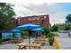 Outdoor patio seating under bright blue umbrellas at NOFO with brick building at 2704 Fairview Rd, Raleigh, NC 27608