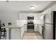 Well-lit kitchen featuring white cabinetry, updated stainless steel appliances, and bar seating at 294 Summerwalk Cir, Chapel Hill, NC 27517