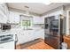 Bright kitchen featuring stainless steel appliances, white cabinets, tile backsplash, and wood flooring at 304 Cornelia Dr, Graham, NC 27253