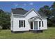 Charming white home with black shutters, front porch, and a well-manicured lawn and mature trees in the background at 305 E Harnett St, Benson, NC 27504
