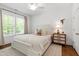 Comfortable bedroom with ceiling fan, light-colored carpet, and large window with green outdoor view at 308 Furches St, Raleigh, NC 27607