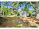View of detached garage in a lush backyard with mature trees and gravel area at 310 Chicopee Rd, Benson, NC 27504