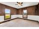 Cozy bedroom with wood paneled walls, carpet, a ceiling fan, and bright windows at 310 Chicopee Rd, Benson, NC 27504