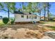 Home exterior with grass, gravel yard, trees and brick foundation at 310 Chicopee Rd, Benson, NC 27504