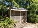 Outdoor backyard shed with brown siding, white trim, and a wooden ramp surrounded by greenery and trees at 312 Heidinger Dr, Cary, NC 27511