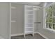Walk-in closet featuring white shelves and a dark metal rod, with a window bringing in natural light at 3204 Peachford Ln, Raleigh, NC 27616