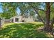 Backyard view with a patio, grill, and grassy area, shaded by mature trees at 3808 Hopper St, Raleigh, NC 27616