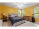 Bright yellow bedroom with two windows and a neutral bed at 404 Cary Pines Dr, Cary, NC 27513