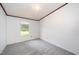 This bedroom features neutral carpet, white walls, and a large window with blinds allowing natural light at 43 Columbus Ct, Spring Lake, NC 28390