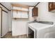 This laundry room features white appliances, overhead cabinets, and built-in shelving for convenient storage and organization at 43 Columbus Ct, Spring Lake, NC 28390