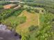 Expansive aerial view showcasing a large plot of land with a pond, fields, and scattered trees at 4314 Hopkins Rd, Middlesex, NC 27557