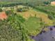 Aerial view of a property featuring a pond, fields, and surrounding trees at 4314 Hopkins Rd, Middlesex, NC 27557