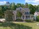Charming two-story home with a stone facade, covered front porch, manicured lawn, and mature trees at 5117 Dove Forest Ln, Apex, NC 27539