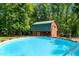 In-ground pool with views of both the log cabin home and matching guest house surrounded by dense trees at 515 Tramway West Rd, Sanford, NC 27330