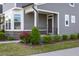 Inviting home entry featuring a covered porch, stone accents, manicured bushes, and seasonal flowers at 5200 Beckom St, Raleigh, NC 27616