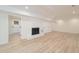 Well-lit basement with a painted brick fireplace and light, laminate wood flooring at 529 Orindo Dr, Durham, NC 27713