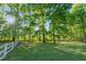 Green grassy yard with a white fence and mature trees at 54 Malcolm Neal Path, Louisburg, NC 27549