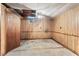 Basement with exposed concrete flooring, wood paneling, and a rustic ceiling fan at 620 Mcghees Mill Rd, Roxboro, NC 27574