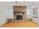 Close-up of a stone fireplace with a wooden mantle and white curtains at 620 Mcghees Mill Rd, Roxboro, NC 27574
