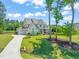 Wide view of a painted brick two story with lush landscaping, large driveway, and a three car garage at 6208 Old Miravalle Ct, Raleigh, NC 27614