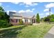 Brick and siding clubhouse with black shutters, mature landscaping, and manicured lawn at 7611 Satinwing Ln, Raleigh, NC 27617