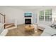Bright living room featuring a cozy fireplace and a sunlit window with verdant outdoor views at 7611 Satinwing Ln, Raleigh, NC 27617