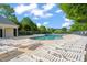 Community pool area with white lounge chairs and mature shade trees on a sunny day at 7611 Satinwing Ln, Raleigh, NC 27617