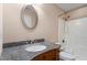 Bathroom features a vanity with dark granite countertop, a large oval mirror and shower with curtain at 97 Rand Rd, Raleigh, NC 27603