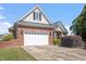 View of the brick home's attached two-car garage with a spacious driveway and manicured lawn at 97 Rand Rd, Raleigh, NC 27603