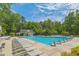 Community pool with lounge chairs, tables, and a lifeguard stand, surrounded by trees at 1 Plowlan Ct, Durham, NC 27707