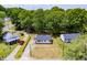 Aerial view of a cozy home with a dark roof, surrounded by lush trees and other charming neighborhood homes at 1013 Graham St, Burlington, NC 27217