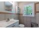 Neutral bathroom with a white toilet and sink, tiled walls, and a window at 1013 Graham St, Burlington, NC 27217
