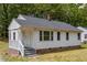 Quaint home with white siding, a covered porch, and a brick foundation nestled in a serene, tree-filled neighborhood at 1013 Graham St, Burlington, NC 27217