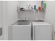 Bright laundry room featuring a modern washer and dryer, along with a shelf for storage and organizing supplies at 104 Vallco Ln, Durham, NC 27713