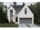 Charming two-story home featuring a gray garage door, gray accents, and stone details surrounding a large arched doorway at 109 Edenburgh Rd, Raleigh, NC 27608