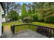 An expansive backyard framed by mature trees is viewed from the dark wood deck at 109 Riverbend Dr, Archer Lodge, NC 27527