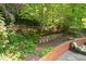 Beautiful lush backyard with a brick wall and lounge seating at 1111 Sourwood Cir, Chapel Hill, NC 27517