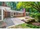 Backyard view of patio, deck, and modern style home surrounded by mature trees at 1111 Sourwood Cir, Chapel Hill, NC 27517