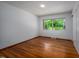 Bright bedroom with hardwood floors, a large window offering backyard views, and closet access at 1111 Sourwood Cir, Chapel Hill, NC 27517