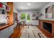 Home office with a modern desk, brick fireplace, hardwood floors, and natural light at 1111 Sourwood Cir, Chapel Hill, NC 27517