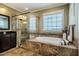 Bright bathroom featuring a standalone tub with tiled surround, shower with glass door, and undermount sink at 113 Ruskin Dr, Chapel Hill, NC 27516