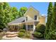 Exterior view of a charming yellow home, featuring a stone patio, well-maintained landscaping, and lush green trees at 150 Georgetown Woods Dr, Youngsville, NC 27596
