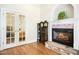 Living room with a cozy fireplace and hardwood floors and doors opening to another room at 150 Georgetown Woods Dr, Youngsville, NC 27596