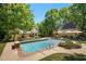 Inviting backyard pool with charming yellow home and pool house surrounded by lush landscaping and patio seating at 150 Georgetown Woods Dr, Youngsville, NC 27596