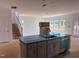 Open-concept kitchen with gray cabinets, island sink and adjacent staircase to upper level at 1609 Malcus Ct # 67, Fuquay Varina, NC 27526
