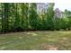 Lush green backyard with mature trees offering ample space for outdoor activities and relaxation at 1820 Yates Wheel Way, Raleigh, NC 27606