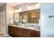 Bathroom featuring a double vanity with granite countertop, decorative mirror, and modern lighting fixtures at 1820 Yates Wheel Way, Raleigh, NC 27606