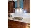 Close up of kitchen cooktop with granite counters, a range hood and wood cabinets at 1820 Yates Wheel Way, Raleigh, NC 27606