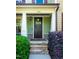 Close-up of front door featuring stone steps and manicured shrubs, offering a warm welcome at 1820 Yates Wheel Way, Raleigh, NC 27606