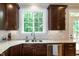 This kitchen features granite countertops, stainless steel appliances, dark wood cabinetry, and a window overlooking the backyard at 1820 Yates Wheel Way, Raleigh, NC 27606